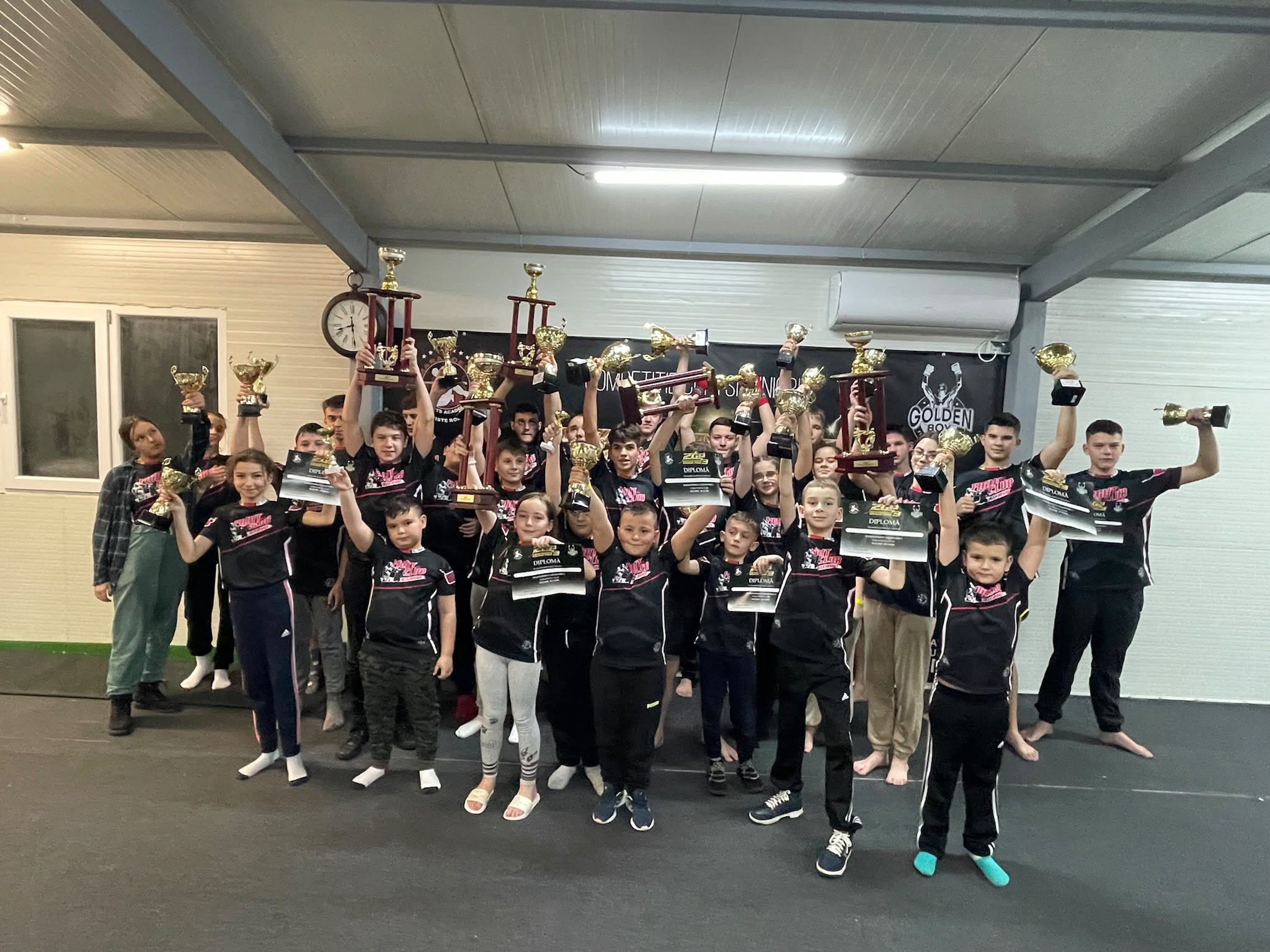 Grup de copii sportivi cu cupe și diplome, Alex Negrea GYM